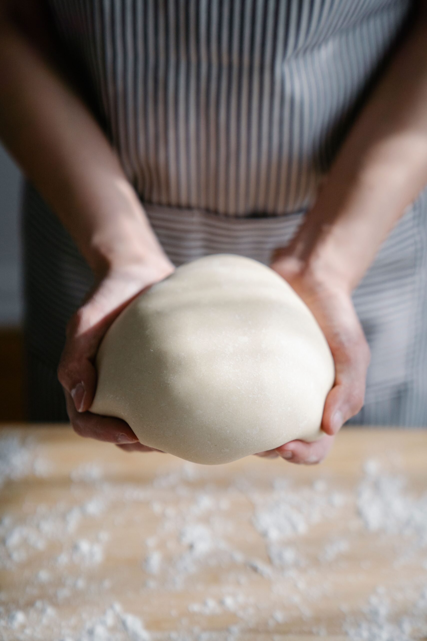 Hands shaping a ball of bread dough