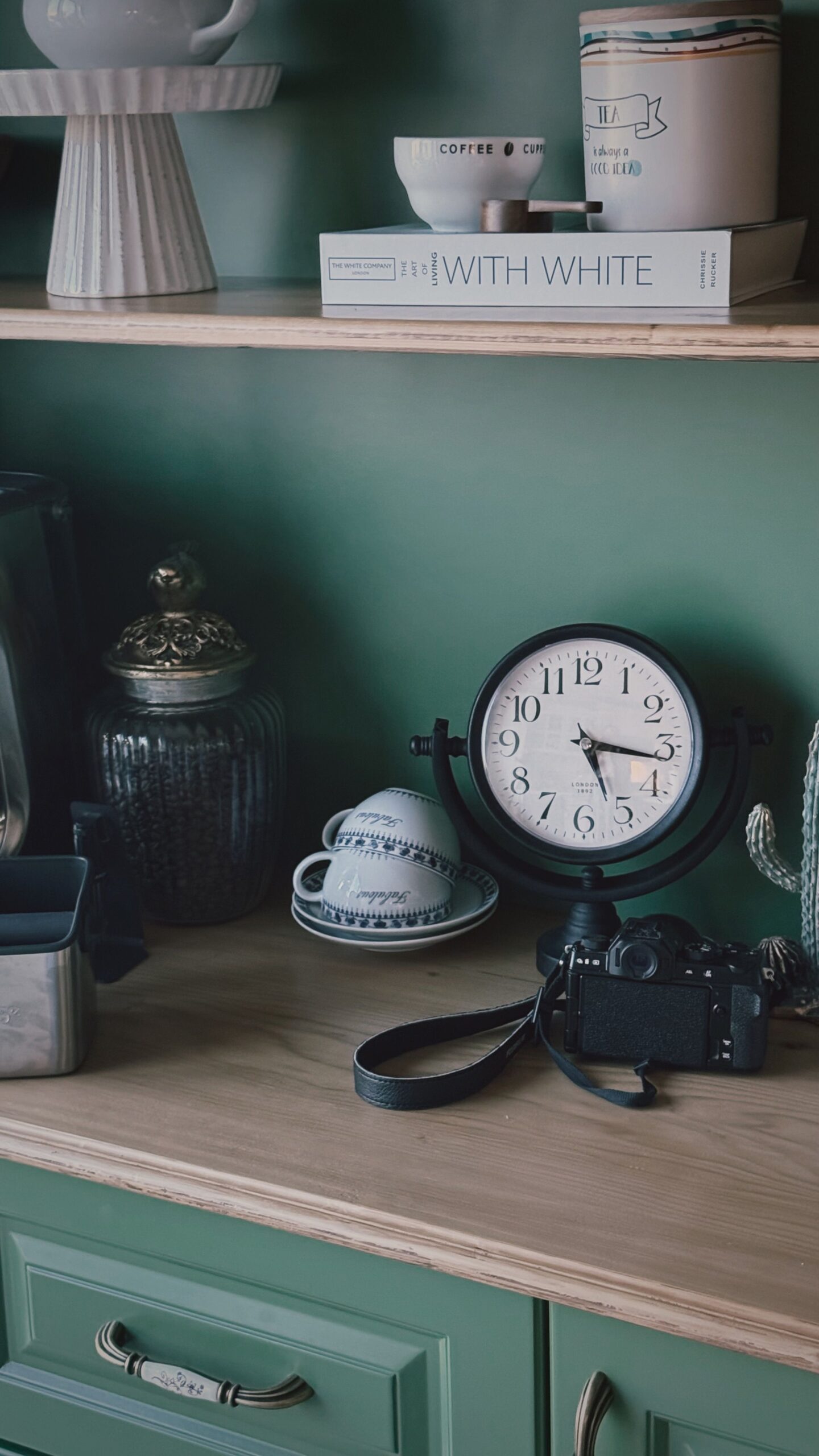 Sage green cabinet with a clock and teacups