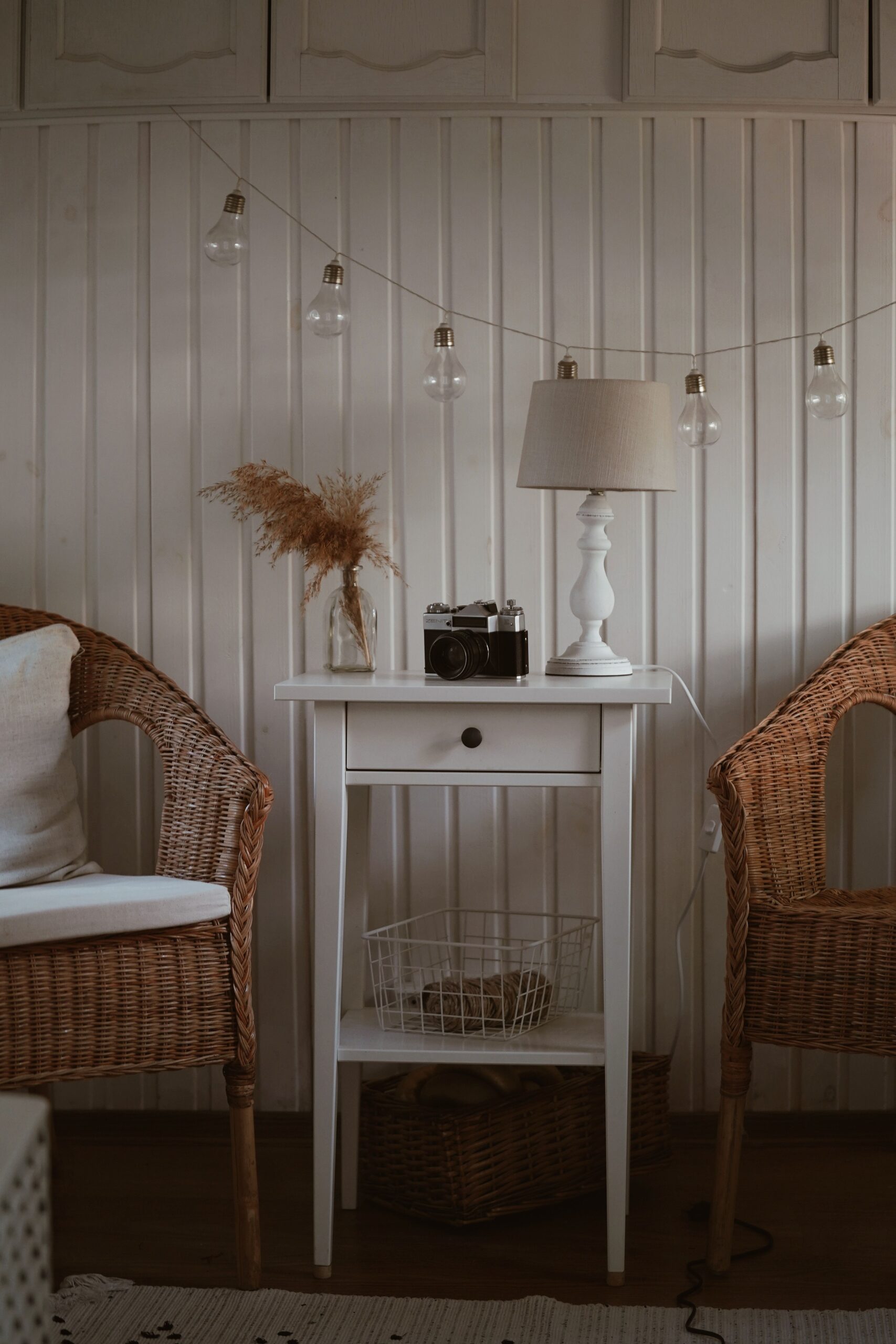 White cottage wall with a side table and wicker chairs